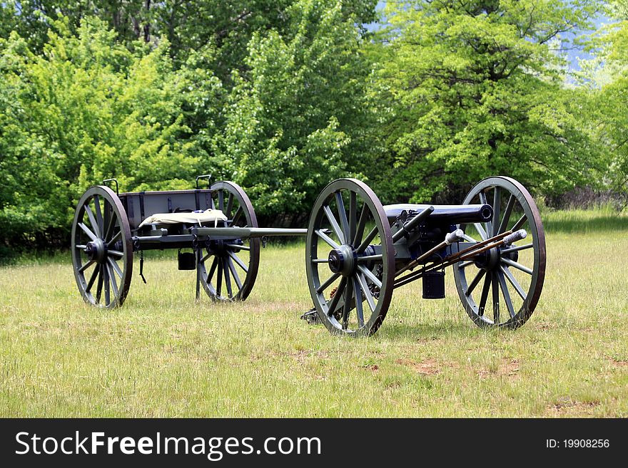 A Cannon from the Civil War era pulling a trailer of ammunition sitting in an open field. A Cannon from the Civil War era pulling a trailer of ammunition sitting in an open field.