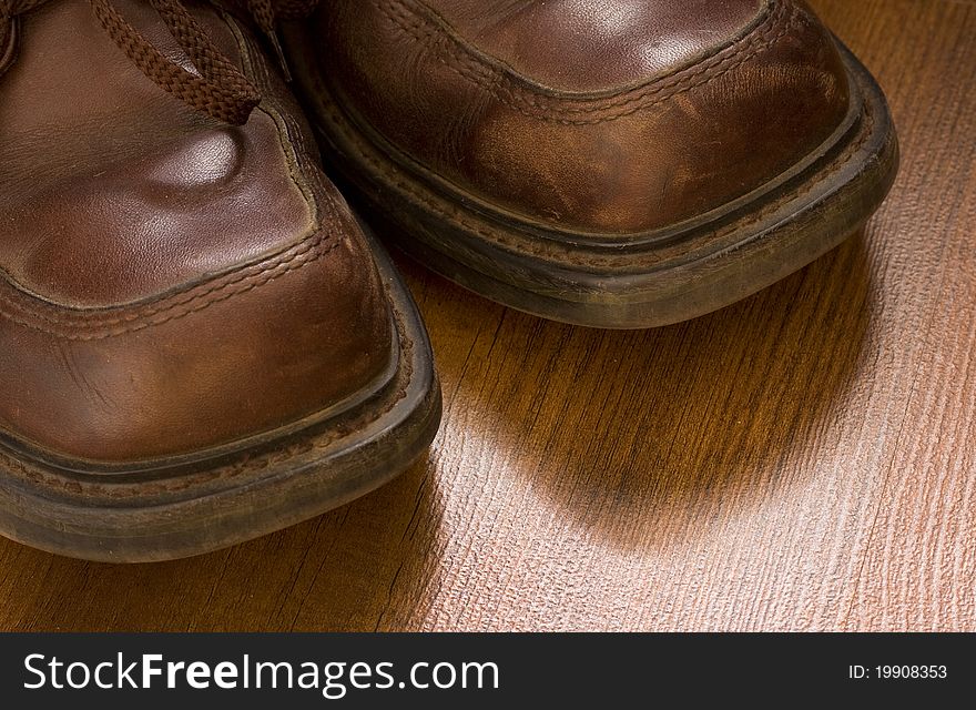 Old worn leather shoes on a wooden floor closeup. Old worn leather shoes on a wooden floor closeup