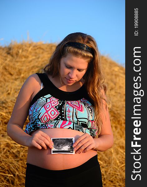 The pregnant girl on a mow with a picture. The pregnant girl on a mow with a picture