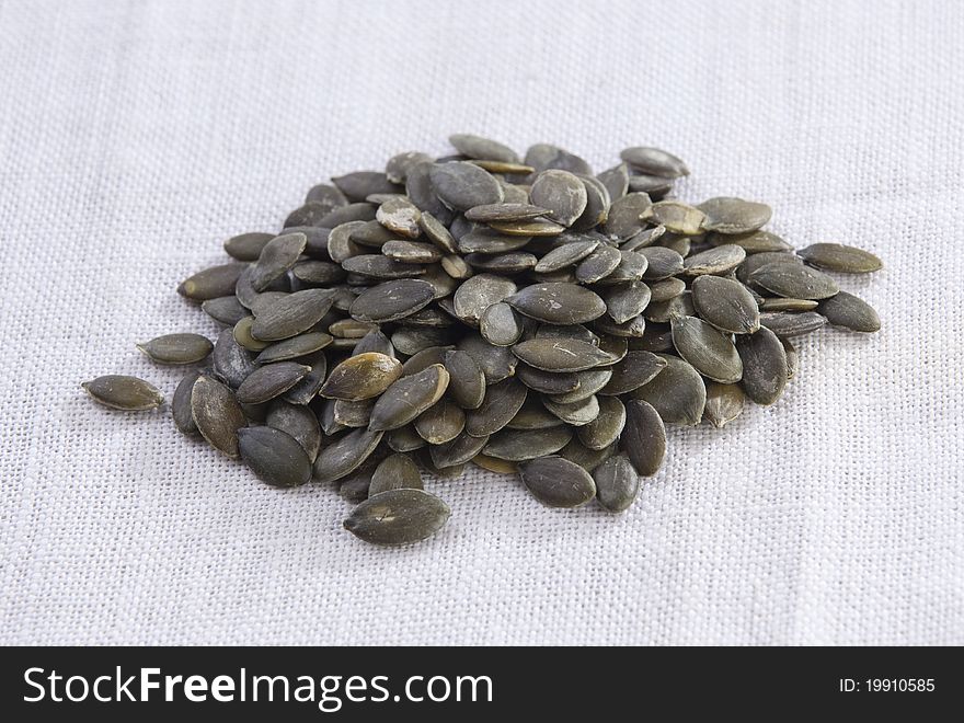 Roasted sunflower seeds on white fabric background. It is a very healthy snack.