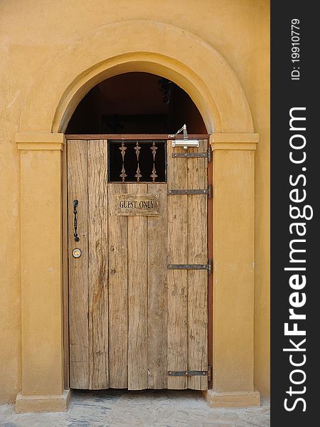 An old wooden door with yellow arch and wall