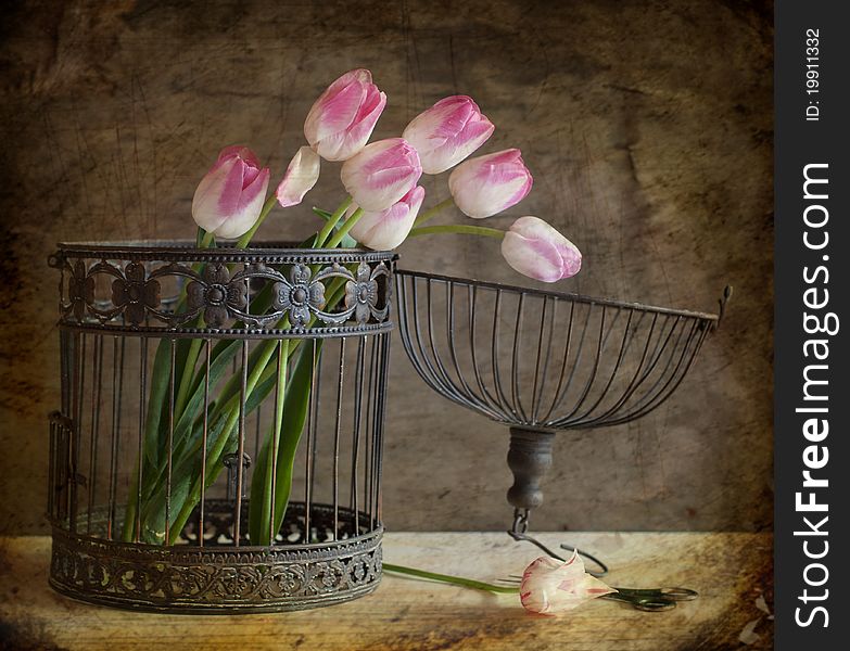 A bouquet of pink tulips is in a cage. A bouquet of pink tulips is in a cage