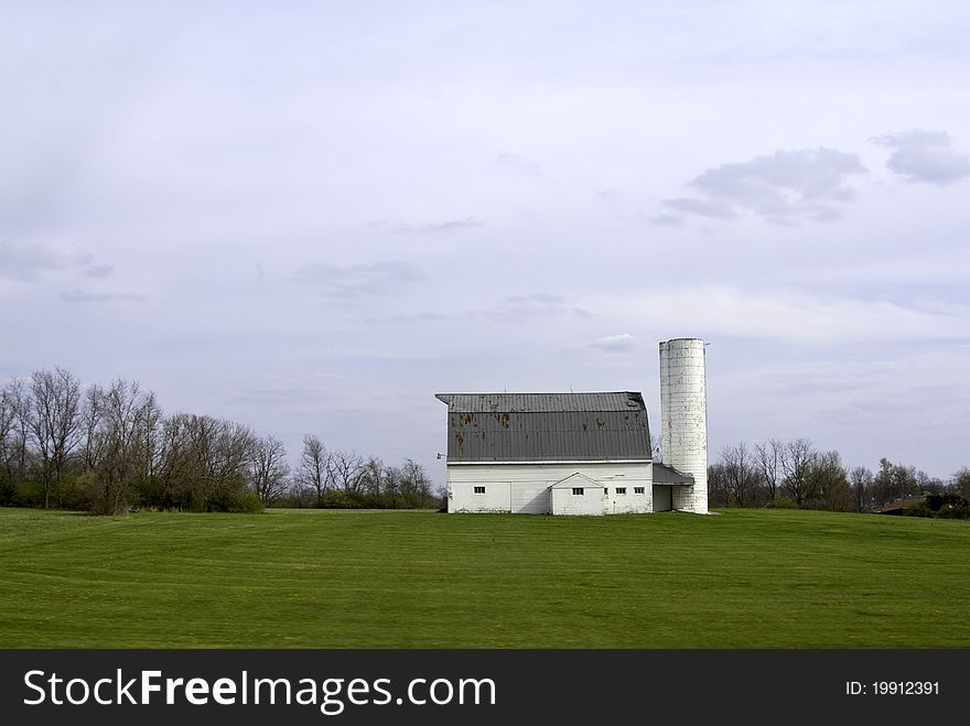 A view of a typical farm with rolling lawns and trees and clouds in the sky. A view of a typical farm with rolling lawns and trees and clouds in the sky.