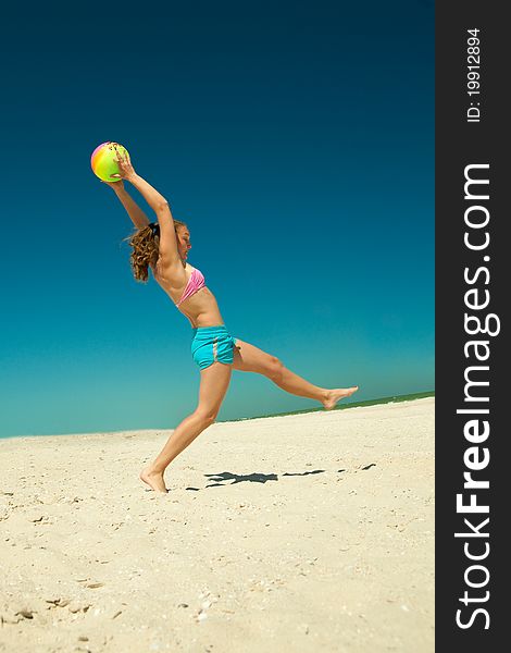 The ecstatic young girl playing volleyball at the beach