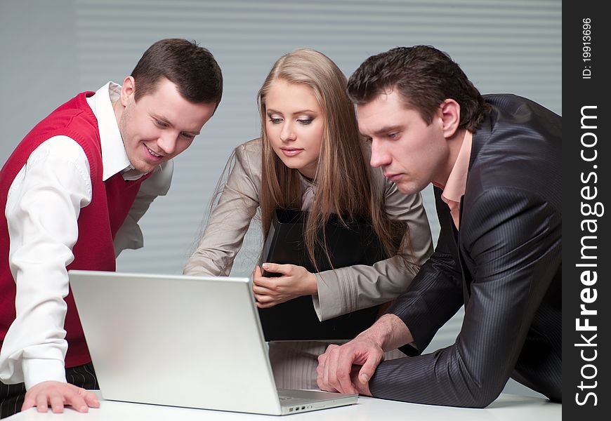 Two men and woman working with a computer in the office