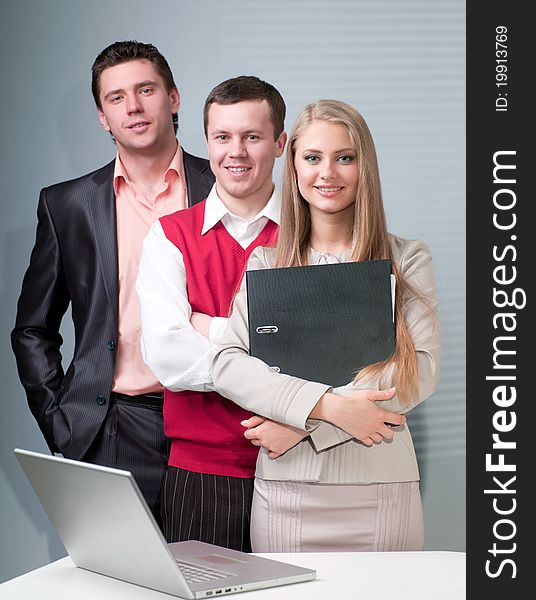 Two men and woman working with a computer