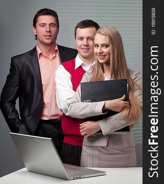 Two men and woman working with a computer