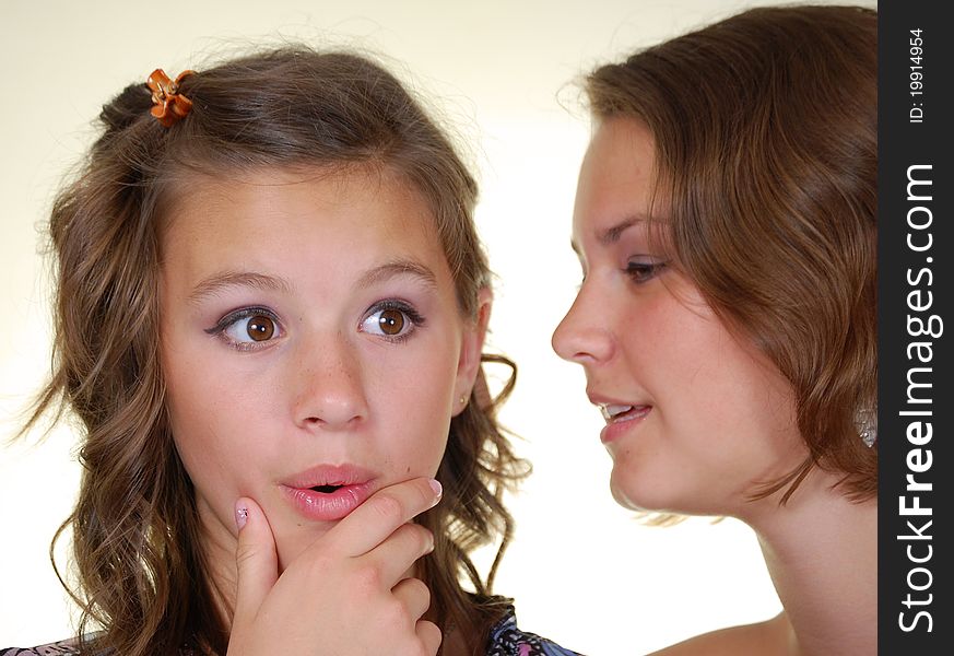 Two happy young girlfriends talking, gossips in secret