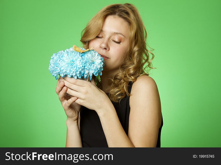 Close-up of an attractive young woman holding a gift bouquet of blue chrysanthemums sits on colors yellow butterfly. Close-up of an attractive young woman holding a gift bouquet of blue chrysanthemums sits on colors yellow butterfly