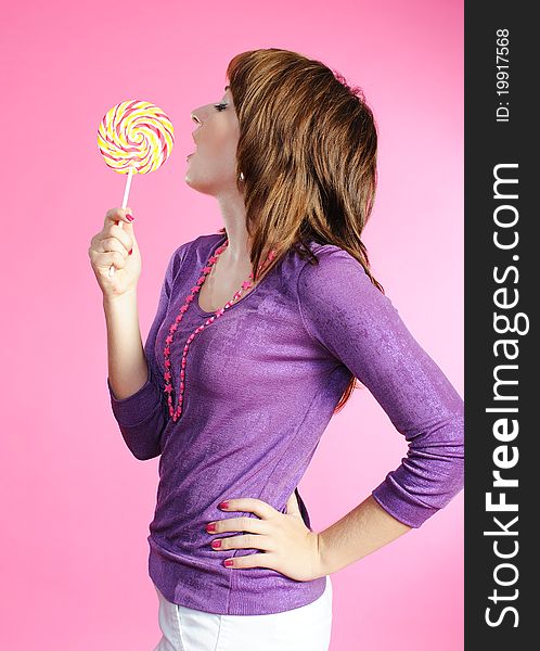 Portrait of girl with lollipop on pink background