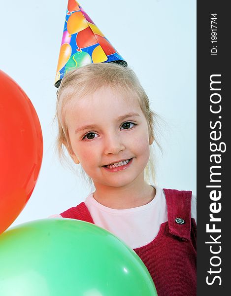 Beautiful little girl with birthday hat play with balloons
