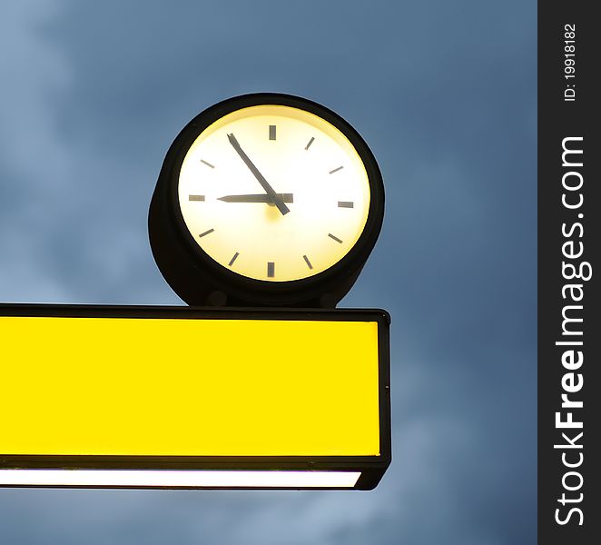 Empty signboard and clock over blue sky background