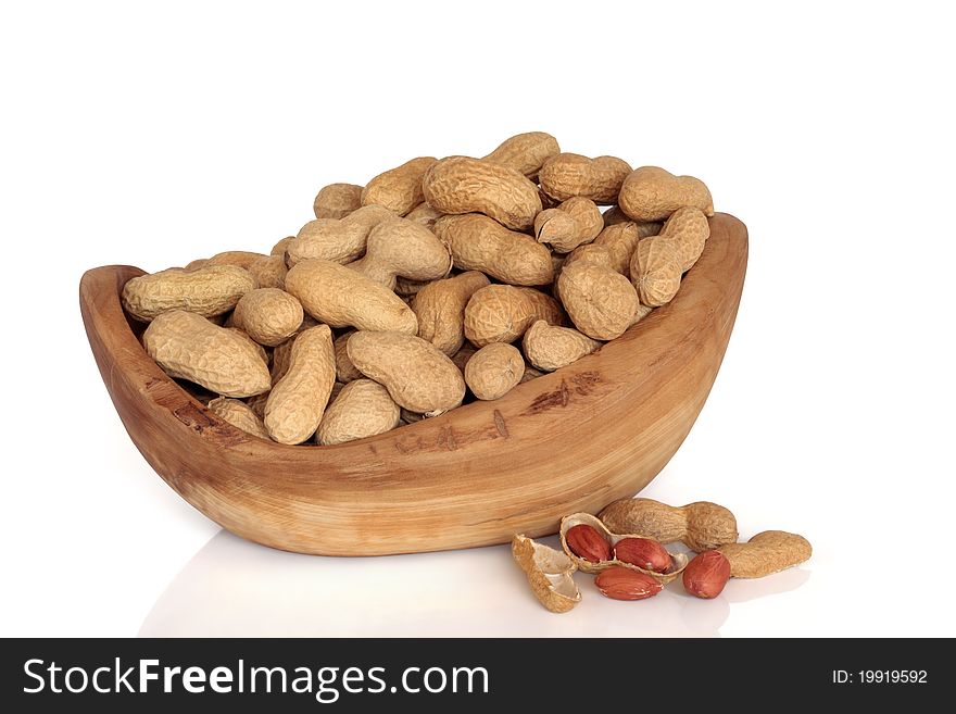 Peanut monkey nuts in an olive wood bowl and scattered isolated over white background. Peanut monkey nuts in an olive wood bowl and scattered isolated over white background.