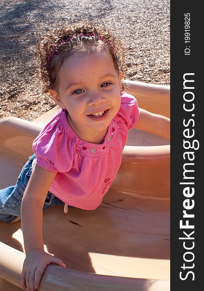 A happy little girl at the park playing on the slide. A happy little girl at the park playing on the slide