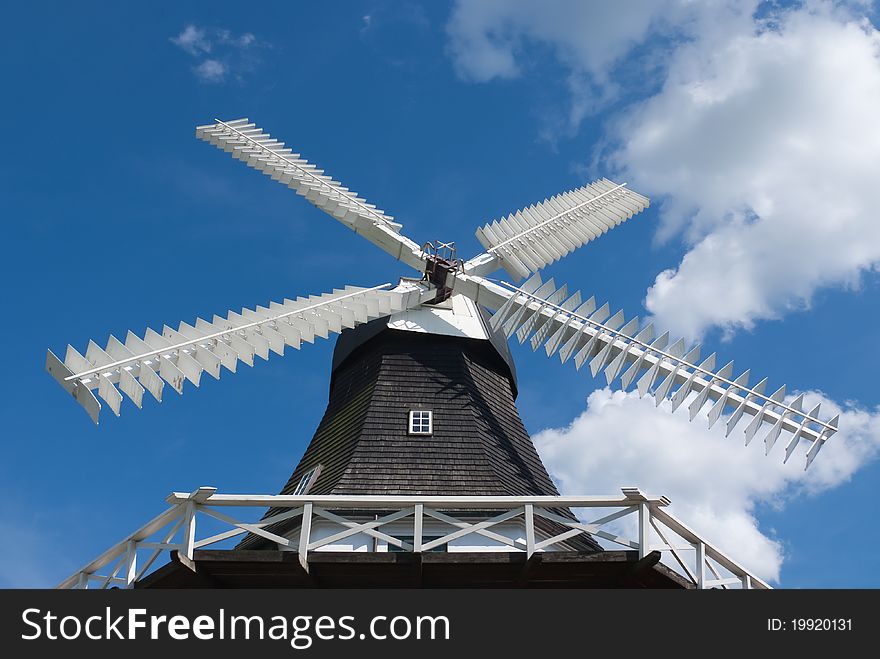Old wooden windmill against blue sky with clouds, Denmark. Old wooden windmill against blue sky with clouds, Denmark.