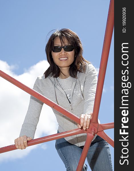 Woman Leans On Playground Bars.