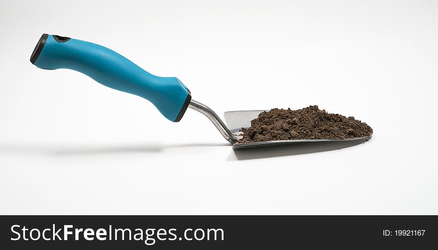 Garden trowel filled with dirt against isolated white background. Garden trowel filled with dirt against isolated white background