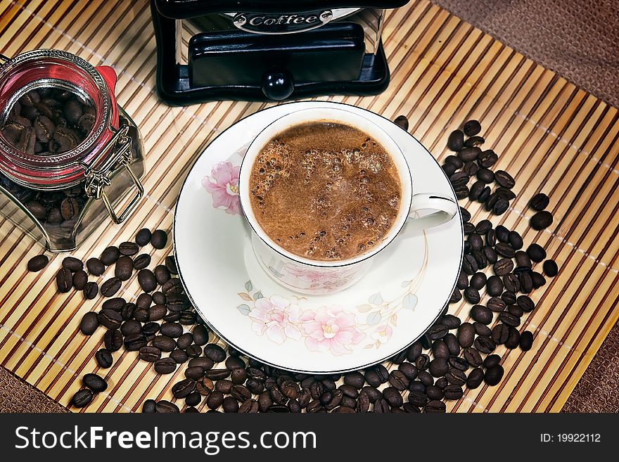 Coffee cup, beans,mill and jar over bamboo mat. Coffee cup, beans,mill and jar over bamboo mat