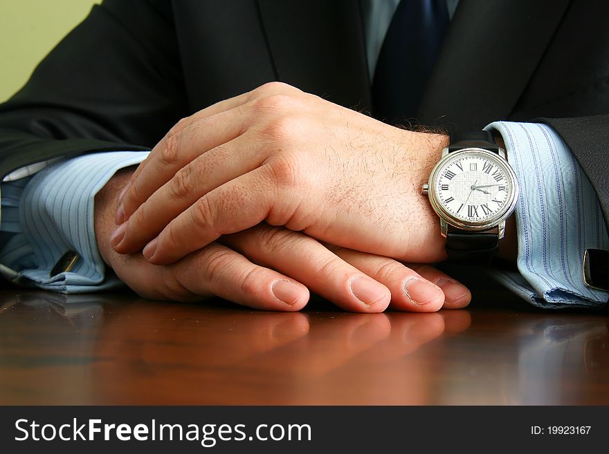 Hands of businessman in suit and shirt with cufflinks and with the clock