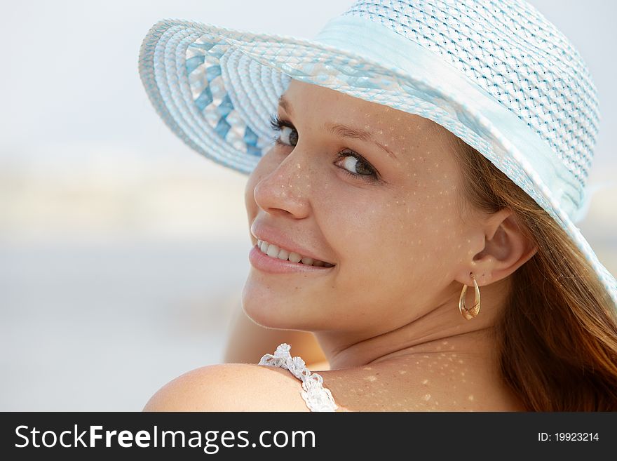 Beautiful happy young woman in straw hat smiling and looking over shoulders on the beach. Horizontal shape, copy space. Beautiful happy young woman in straw hat smiling and looking over shoulders on the beach. Horizontal shape, copy space