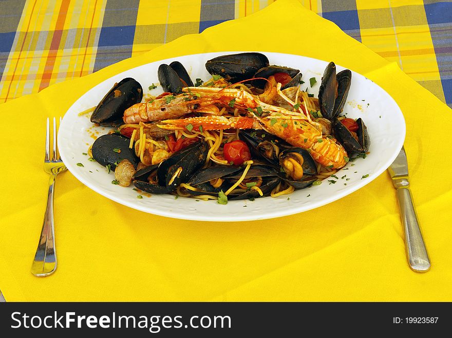 Spaghetti with sea food and tomato of the table prepared with yellow cloth