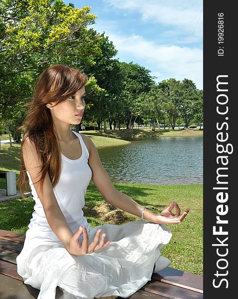 Young Girl Meditating In The Park