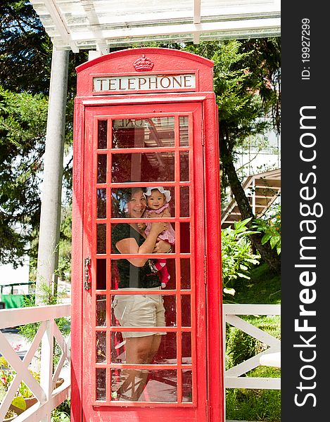 Mother and child inside vintage red London styled telephone booth. Mother and child inside vintage red London styled telephone booth