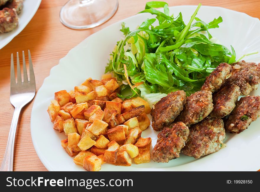 Meatballs with beef and spices, fries potatoes and salad. Meatballs with beef and spices, fries potatoes and salad