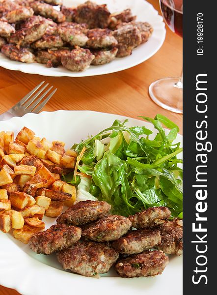 Meatballs with beef and spices, fries potatoes and salad
