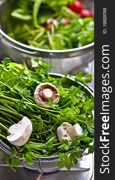 Some mushrooms with parsley in the foreground and radishes with other greens in the background. Some mushrooms with parsley in the foreground and radishes with other greens in the background