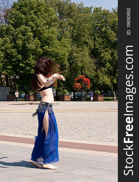 Dancing woman in city square on sunny day in summer