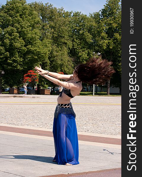 Dancing woman in city square on sunny day in summer
