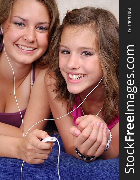 Two beautiful young teenager listening to their MP3 players. Two beautiful young teenager listening to their MP3 players