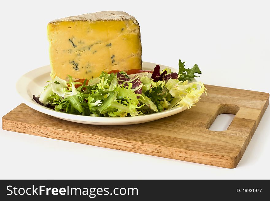 British blue cheese and salad on a white plate on a wooden cheese board