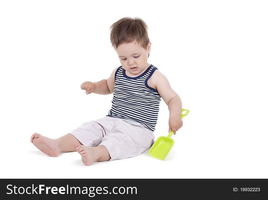 Child playing  with a toy shovel on a white background. Child playing  with a toy shovel on a white background