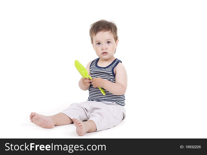 Child playing  with a toy shovel on a white background. Child playing  with a toy shovel on a white background