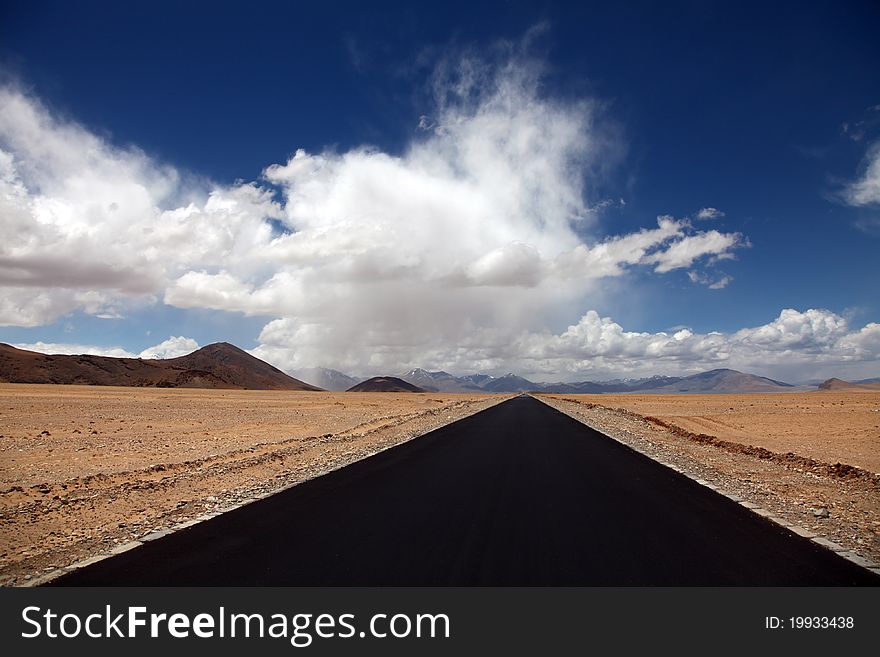 A blacktop road vanishing under beautiful cloudscape. A blacktop road vanishing under beautiful cloudscape