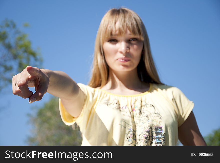 Portrait of the young woman pointing a finger against the blue sky. Portrait of the young woman pointing a finger against the blue sky