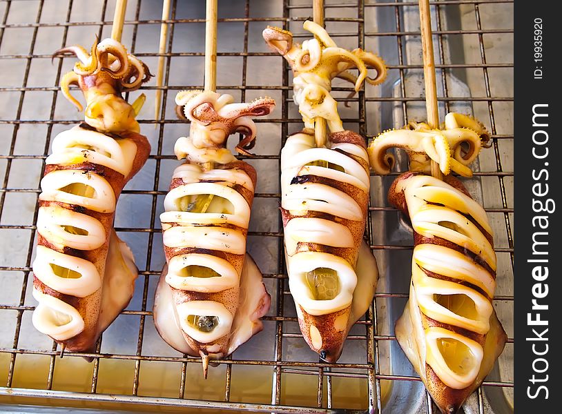 Skewered squid on wooden sticks grilled tentacles , market Thailand