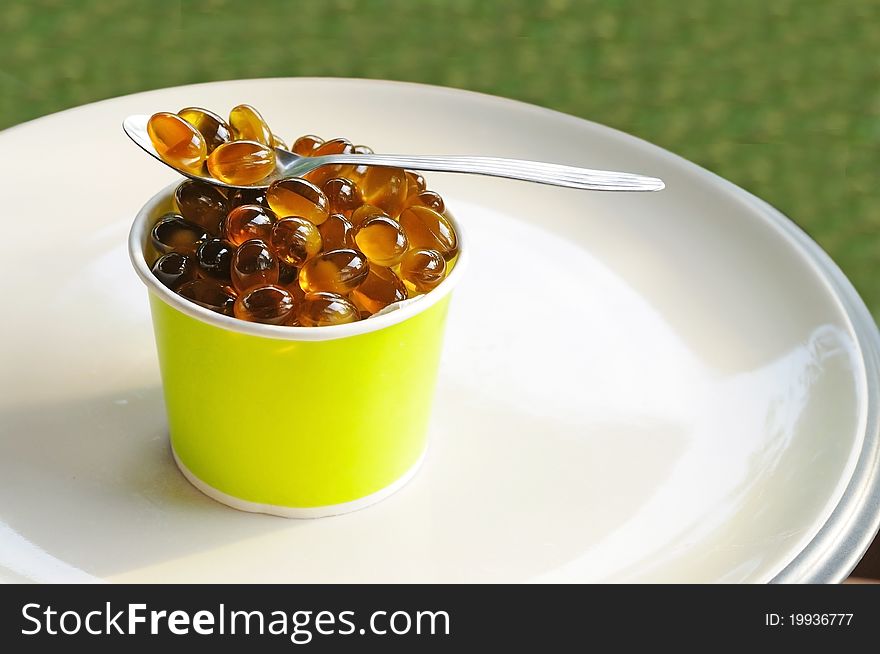 Oil capsule in dessert cup and spoon