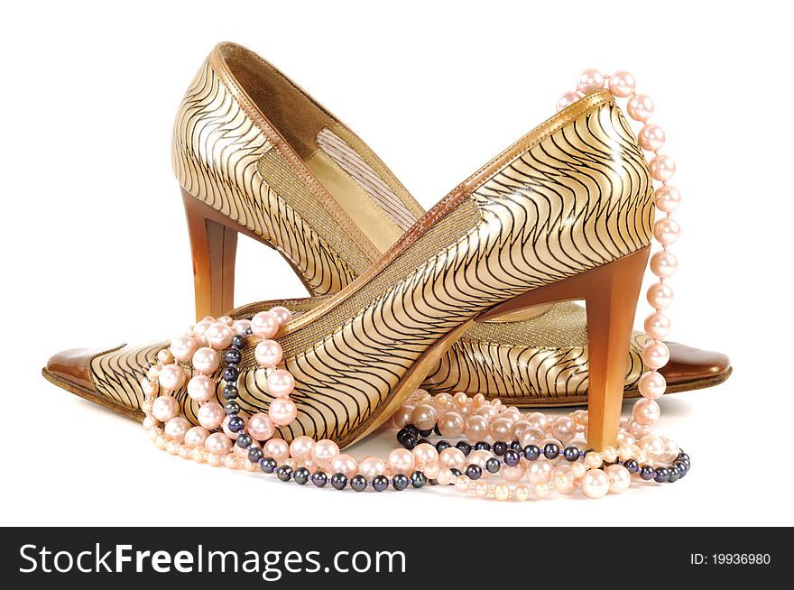 Woman golden shoe with pearl necklace   on a white background