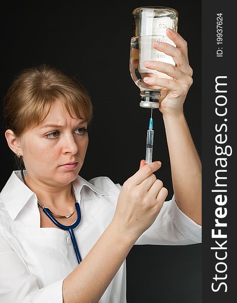 Nurse, is gathering a syringe for injection (medical black background)