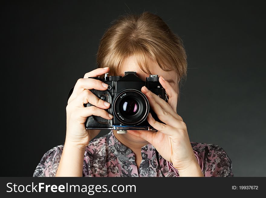 Portrait of a girl with a camera on a dark background