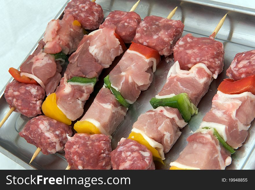 Skewers of raw meat and peppers, white background