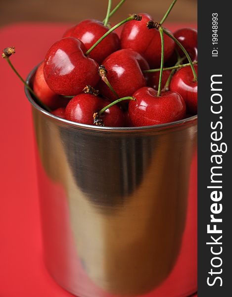 Fresh cherries in a metal cup on a red background. Fresh cherries in a metal cup on a red background.