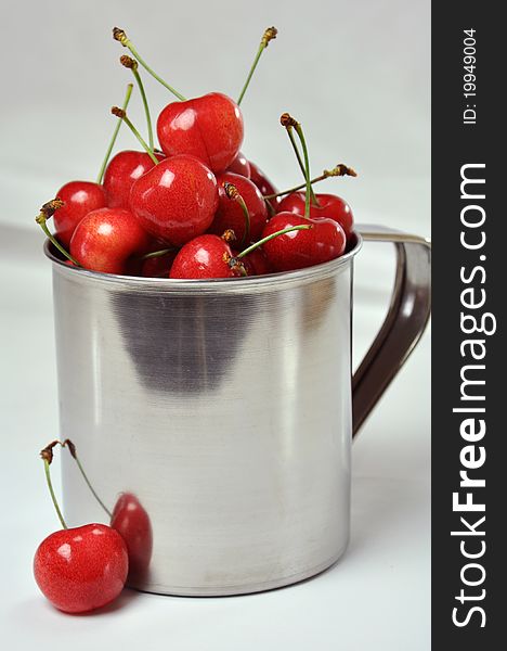 Fresh cherries in a metal cup on a white background. Fresh cherries in a metal cup on a white background.
