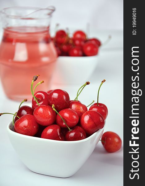 Fresh cherries in white bowls and a jug on a white background. Fresh cherries in white bowls and a jug on a white background.