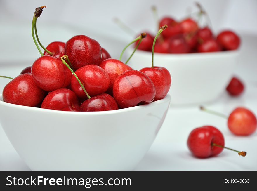 Fresh cherries in white bowls on a white background. Fresh cherries in white bowls on a white background.