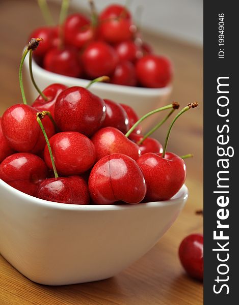 Fresh cherries in white bowls on a wooden table. Fresh cherries in white bowls on a wooden table.