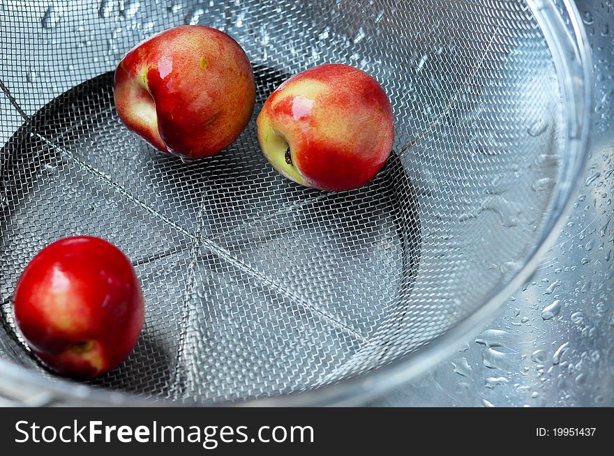 Three peaches getting cleaned while being rinsed with water. Three peaches getting cleaned while being rinsed with water